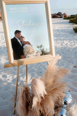 Photograph of bride and groom embracing in a mirror at their beach wedding ceremony