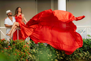 Photograph of couple doing an editorial photoshoot. The woman is wearing a flowing red dress.