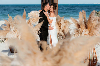 Photograph of bride and groom embracing at their beach wedding ceremony