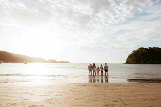 Photograph of a family holding hands in the sea in the late afternoon taken by a DreamArt photographer