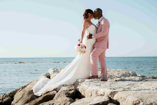 Photograph of bride and groom kissing on the rocks of a Jamaican beach