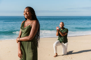 A man proposing to his girlfriend on one knee with a diamond engagement ring during a proposal photoshoot in Cancun on the beach