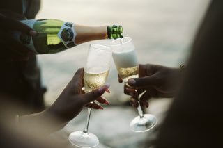 A romantic couple cheers with two glasses of champagne overlooking the ocean during an proposal photoshoot in Cancun