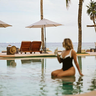 Photoshoot by photographer of woman sitting in the infinity pool with cocktail at Viceroy Riviera Maya