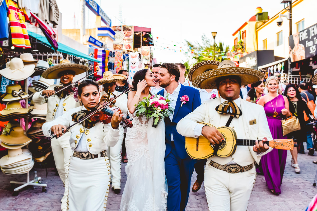 Newlyweds walking at the fifth avenue playa del carmen with mariachis