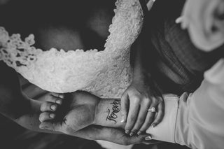 bride holding the hand of the groom showing the tattoo forever
