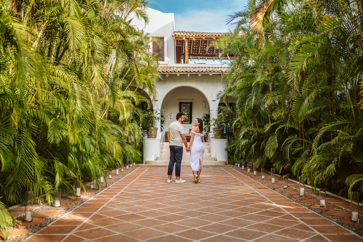 Couple walks hand in hand along a palm-lined terracotta path at Hotel Esencia in the Riviera Maya