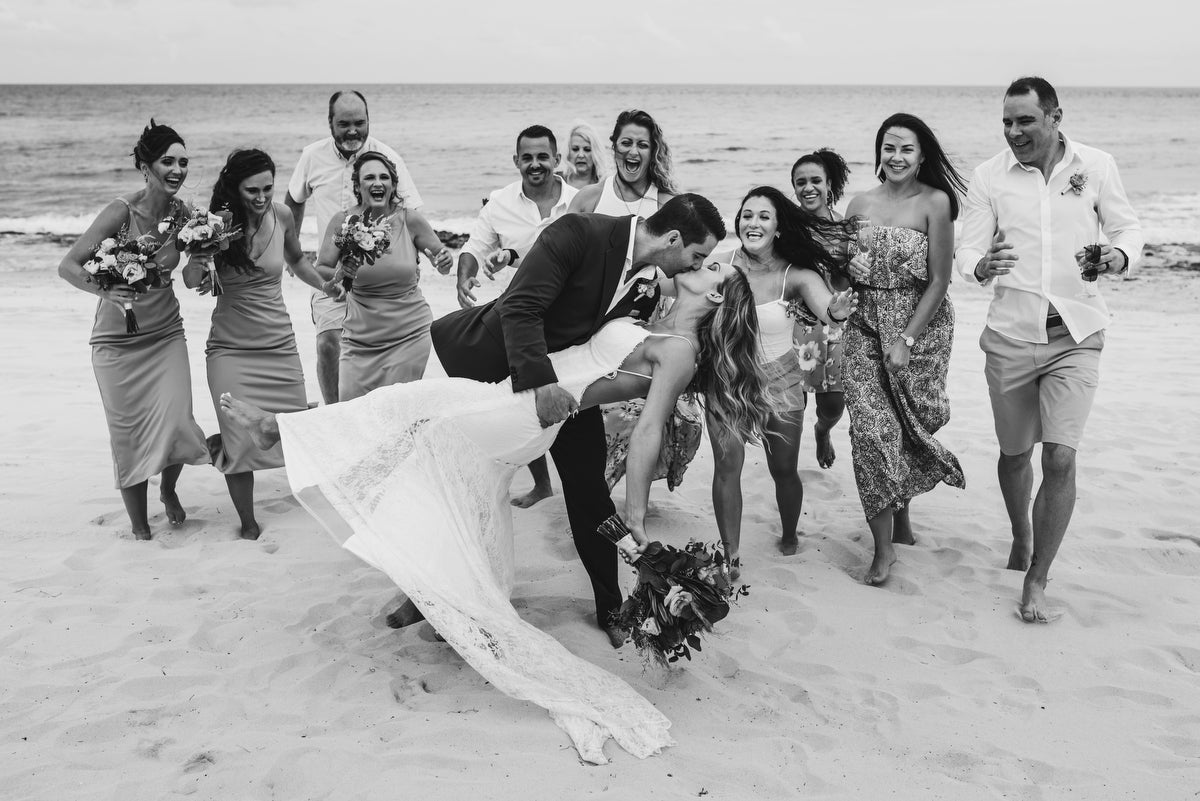 Newlyweds kissing in the beach in front of all our their guests