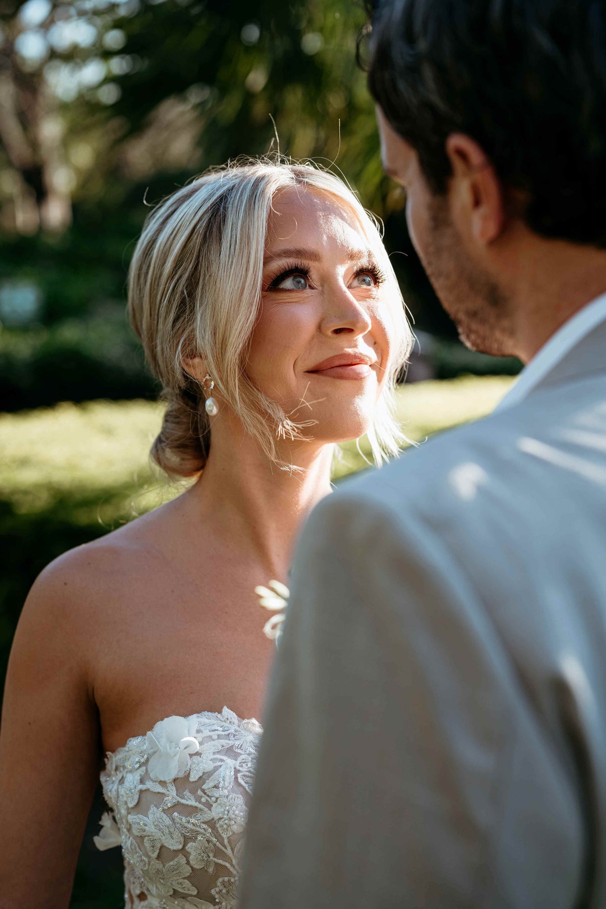 Photograph of bride looking longingly at the groom. There is a focus on her pearl earring, captured by a DreamArt photographer