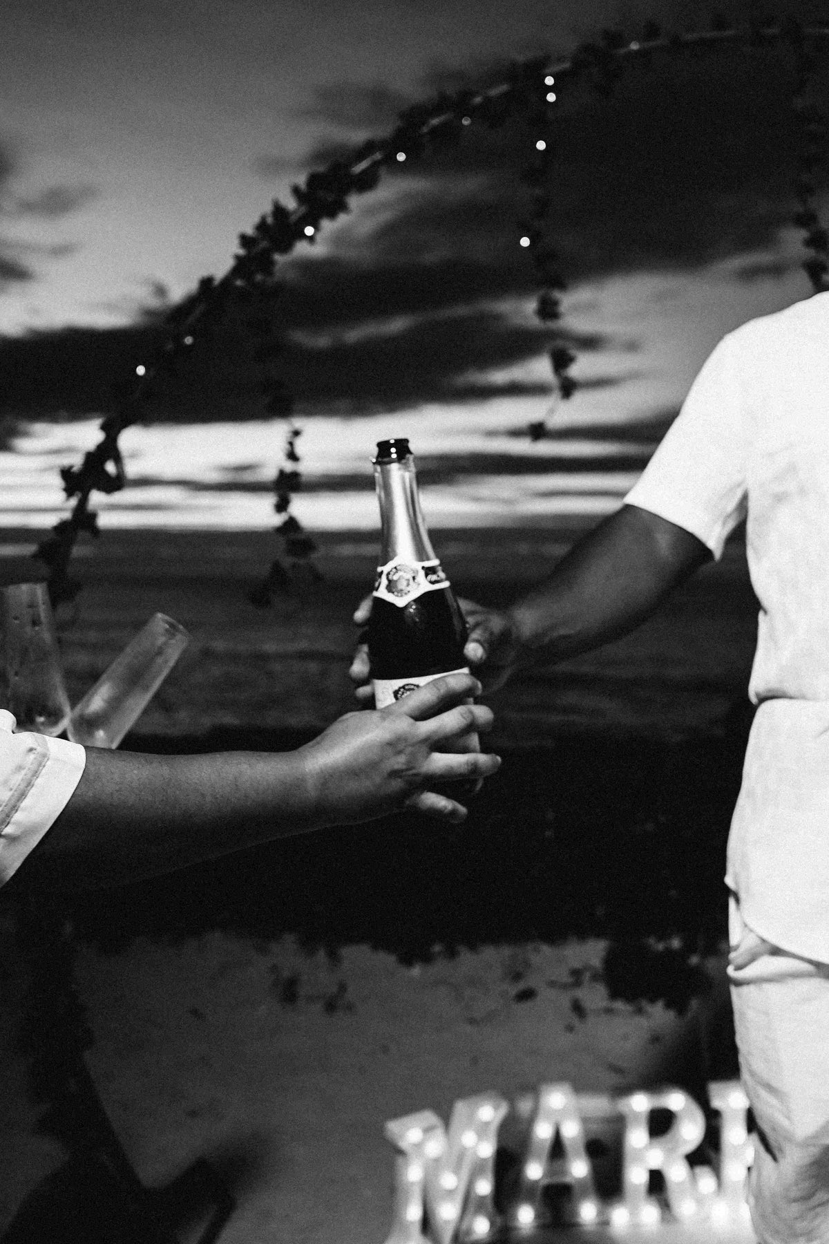 Photograph of a bride and groom handling a bottle of champagne, captured by a DreamArt photographer