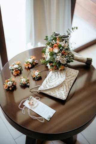 Photograph of a wedding flat lay. There are flowers, a bag and a vows sheet, captured by a DreamArt photographer