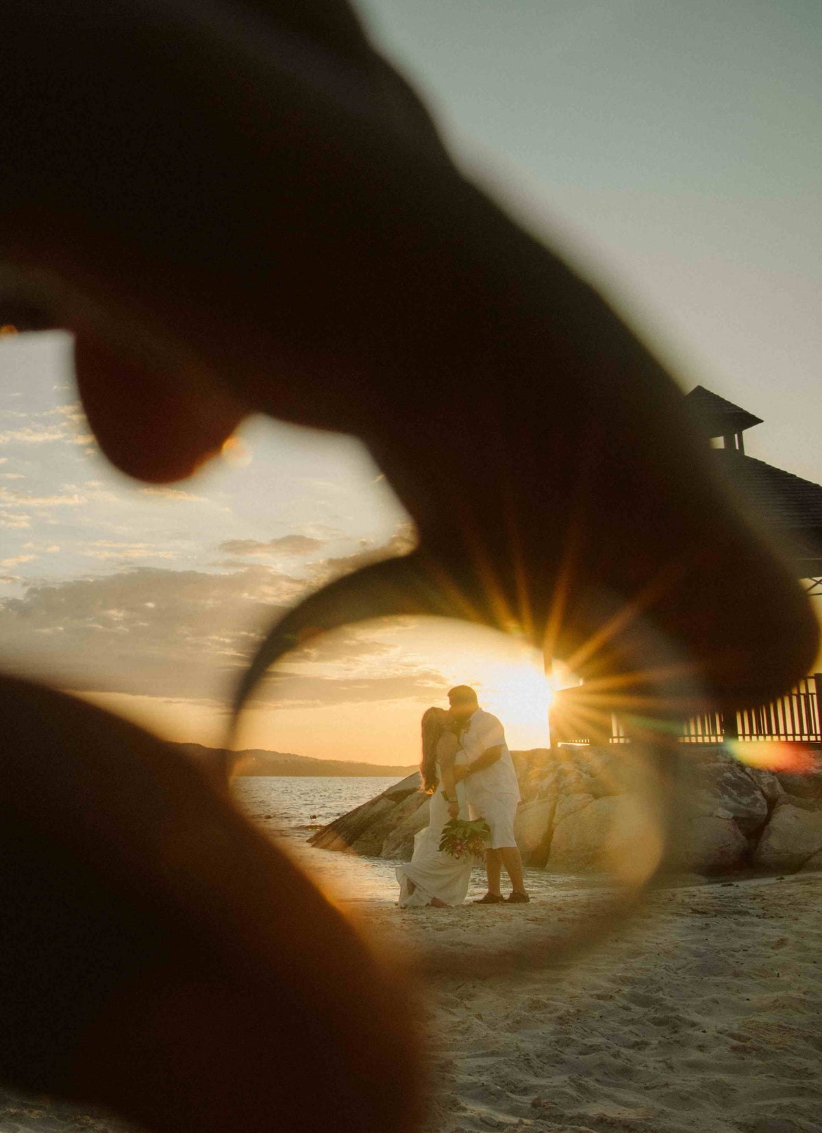 Couple kisses at sunset seen through a wedding ring held up to the lens at Zoëtry Marigot Bay St. Lucia