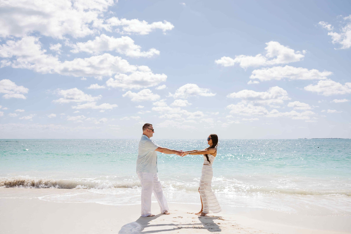 Photograph of a couple holding hands on the beach, captured by a DreamArt photographer