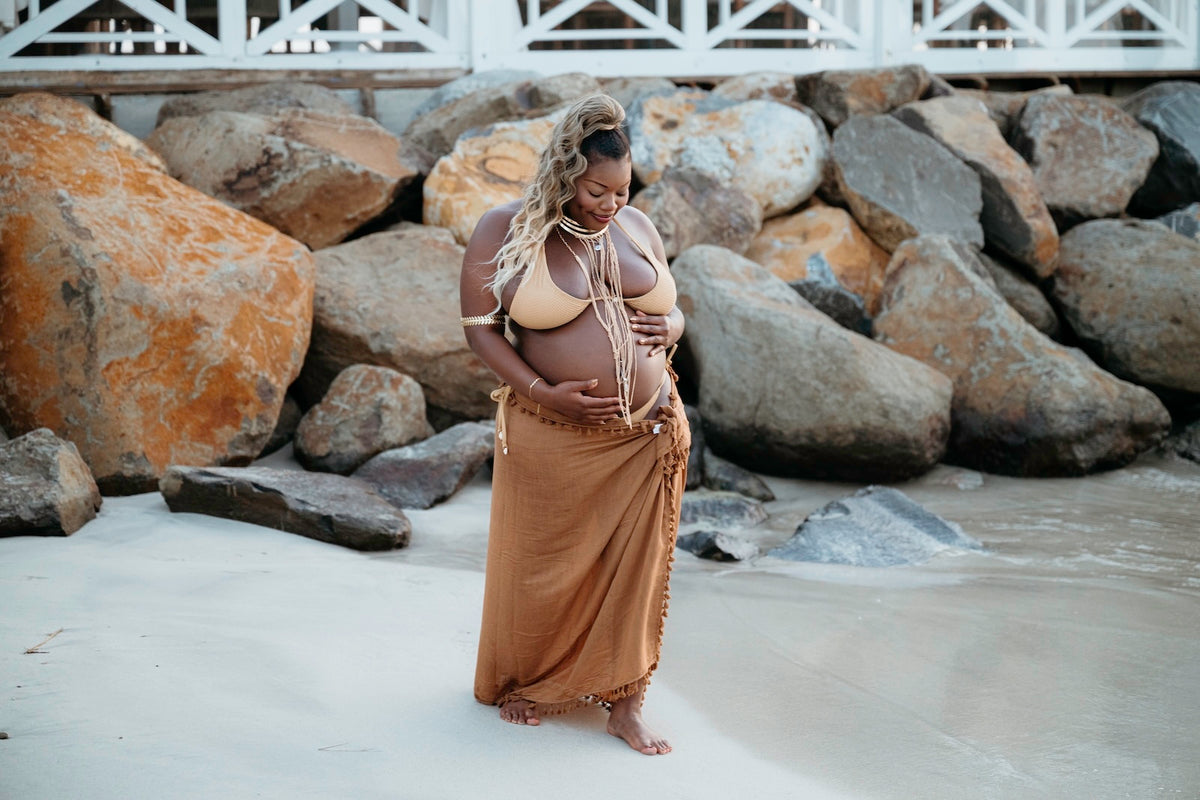 Photograph of a pregnant woman holding her baby bump at the beach of Secrets St. Lucia