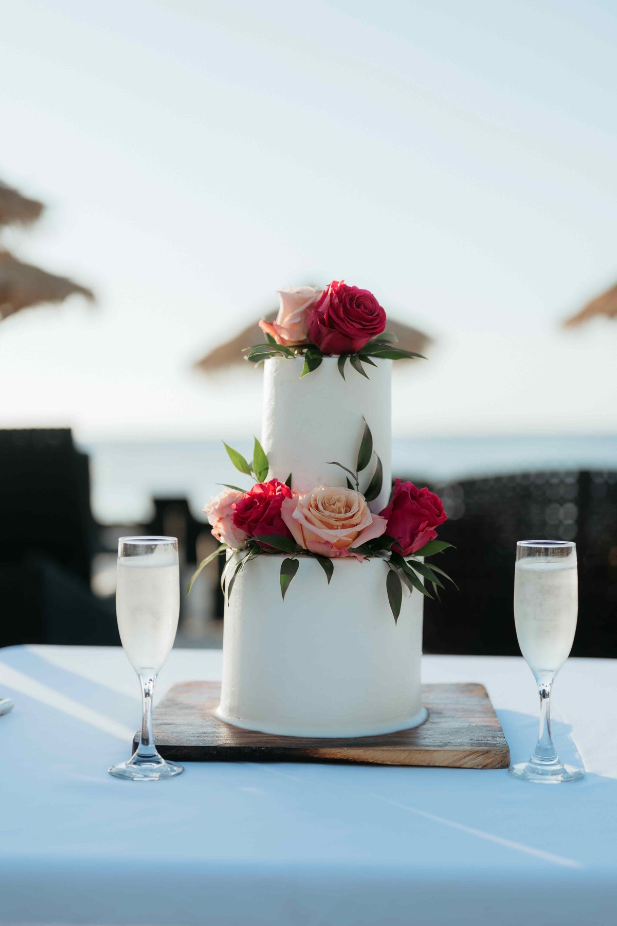 Photograph of a floral wedding cake on the beach, captured by a DreamArt photographer