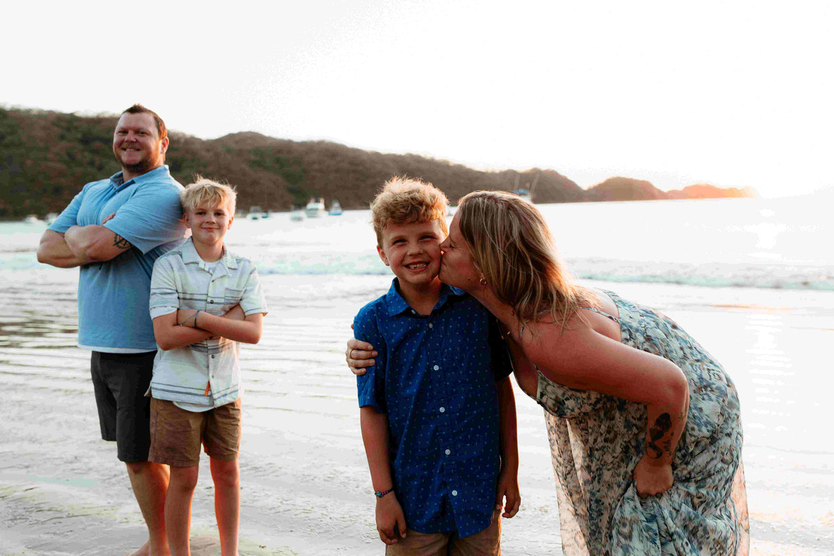 Photograph of a family of 4 posing on the beach, captured by a DreamArt photographer