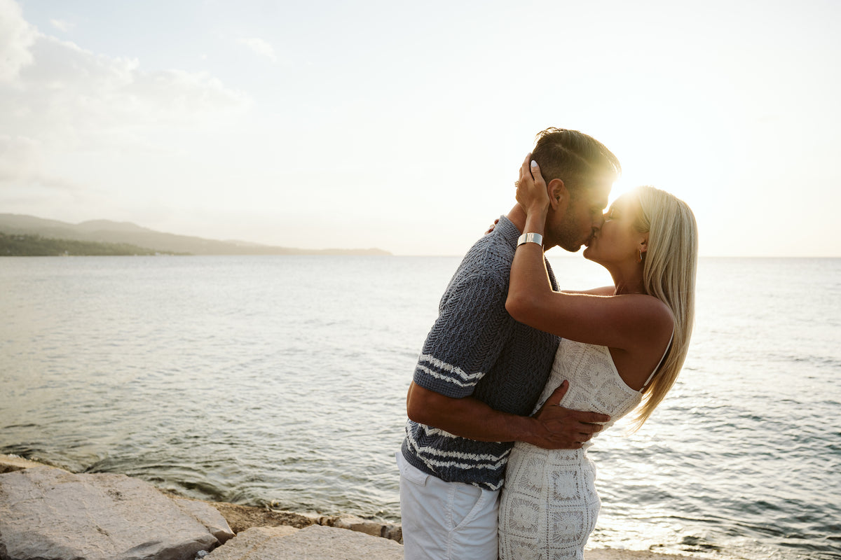 Couple kisses on the rocky shoreline at sunset during a couples photoshoot in Montego Bay, Jamaica