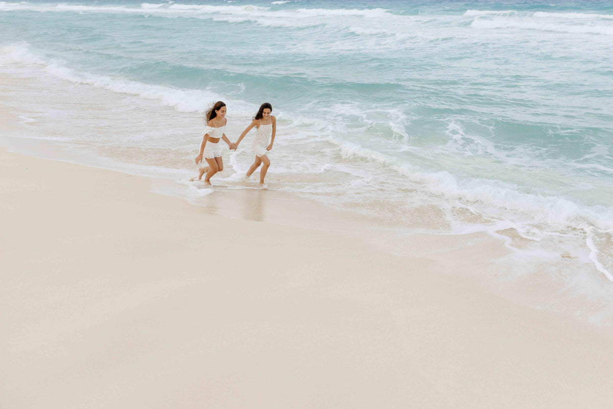 Photograph of two girls running along the beach holding hands