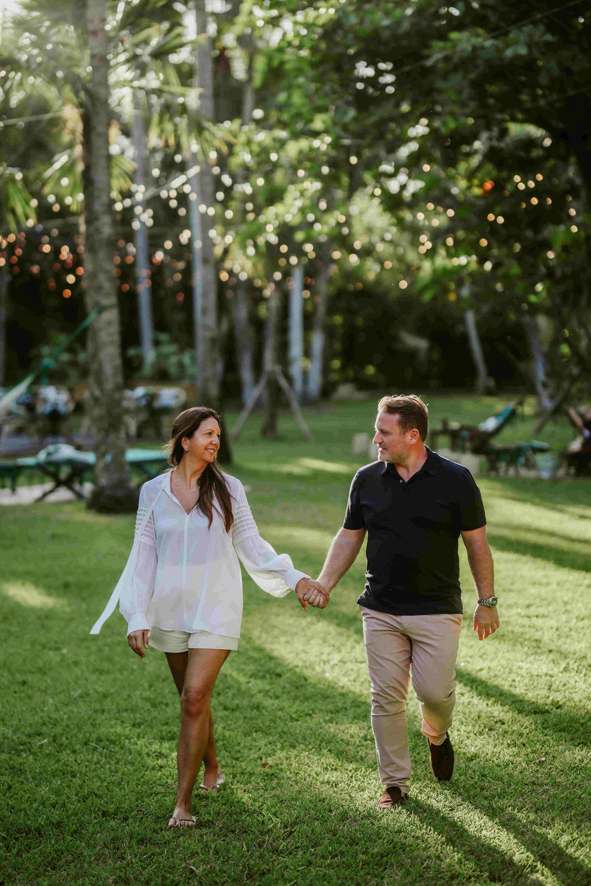 Photograph of husband and wife holding hands walking through the lush gardens of Hotel Esencia