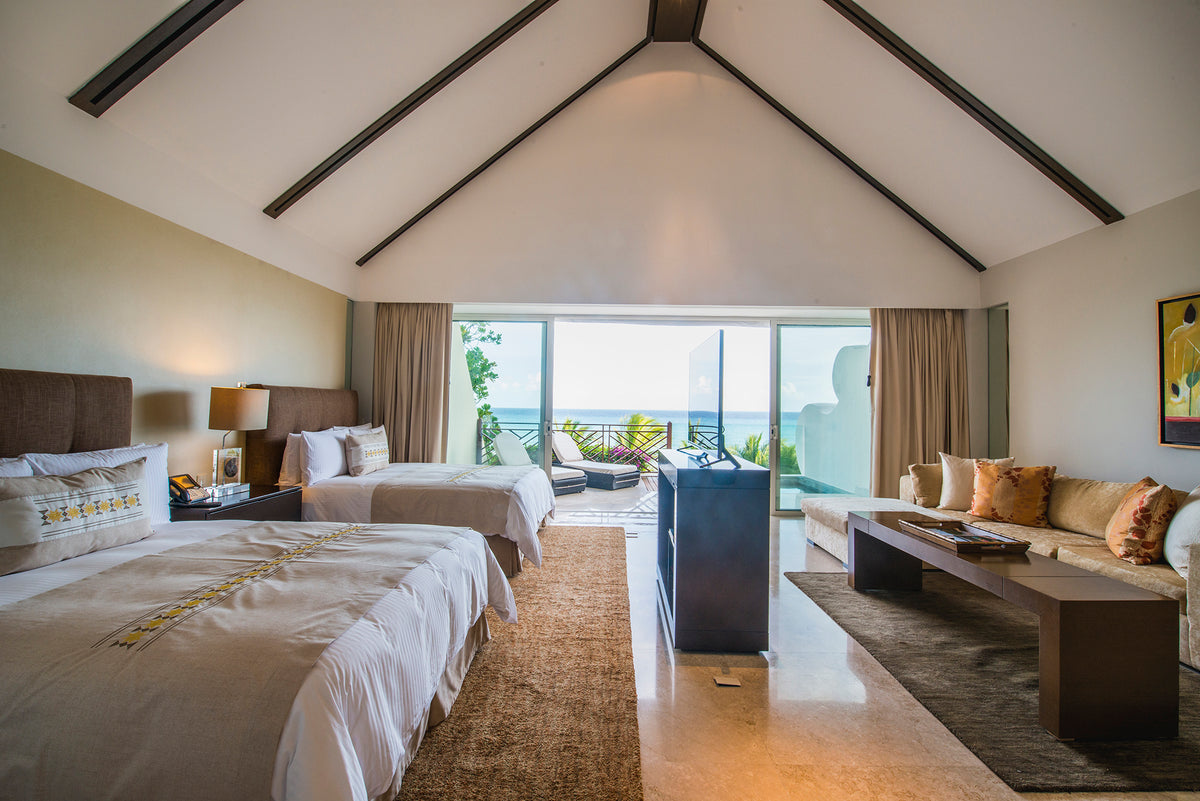 Grand Velas presidential suite with two beds and a vaulted beamed ceiling opening onto an ocean terrace, before editing
