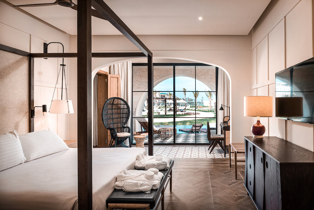 Bright suite with a four-poster bed and arched glass doors opening onto the pool at H10 Ocean El Faro