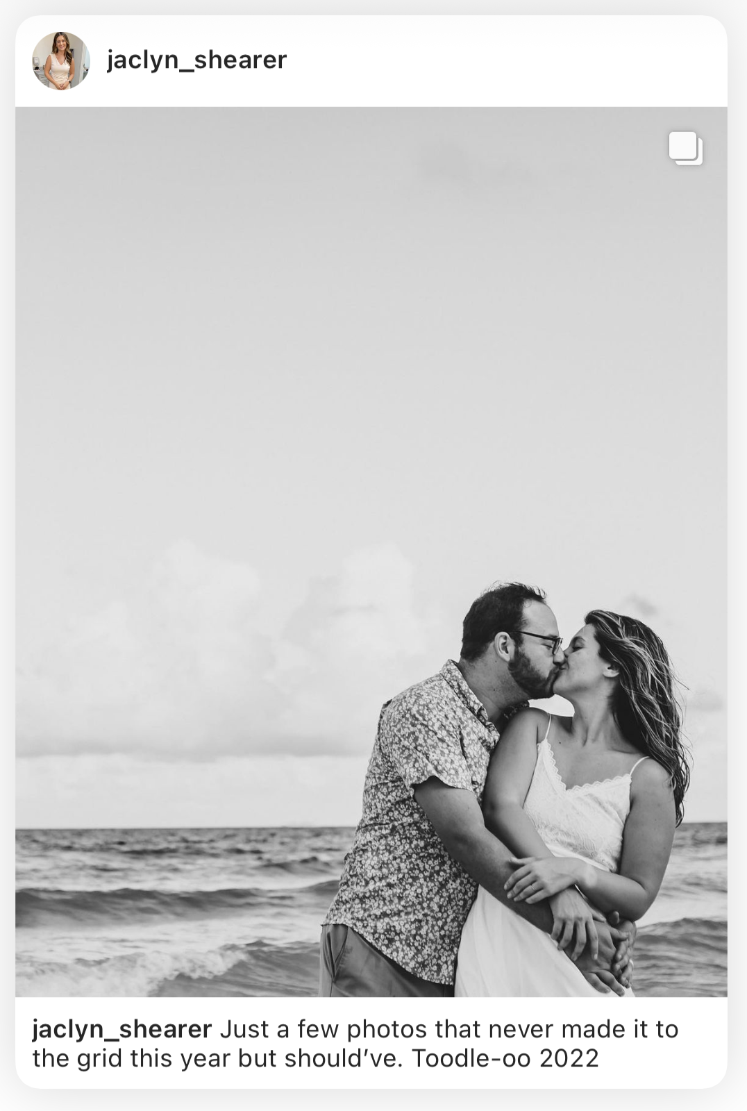 Black and white Instagram post of a couple kissing in front of the waves