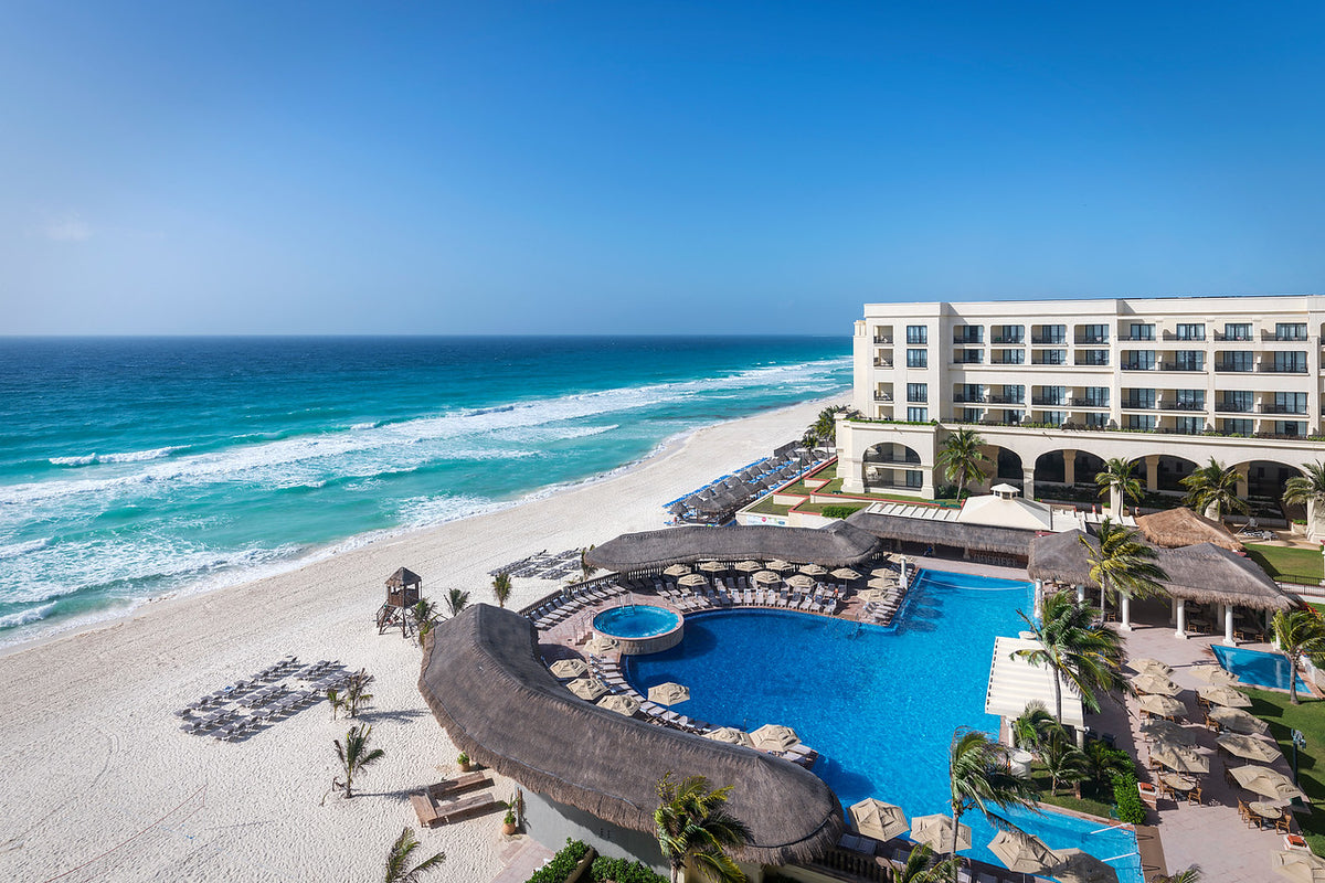 Aerial hotel photography of the beachfront pools, palapas and turquoise sea at JW Marriott
