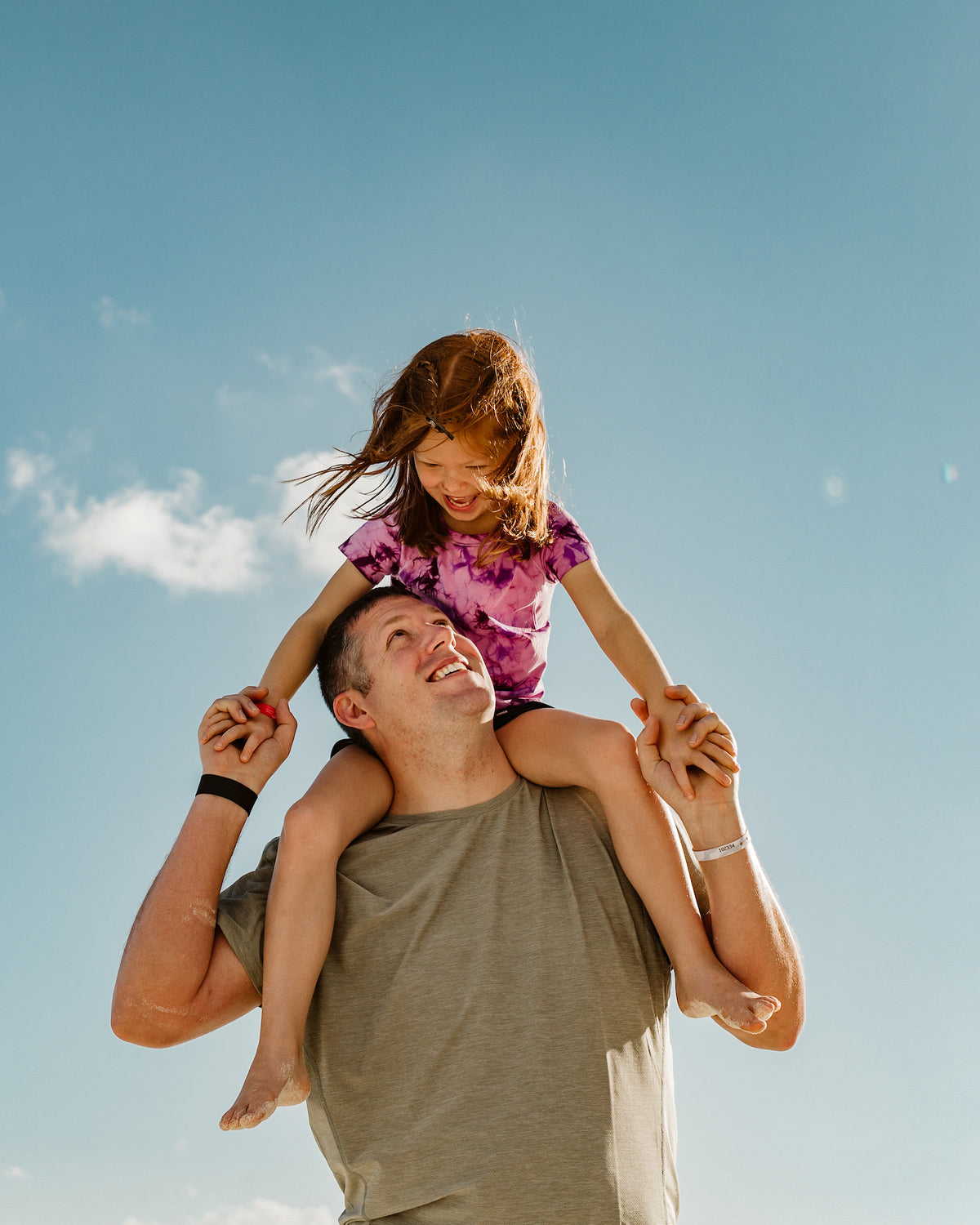 A man carries a laughing girl on his shoulders against a blue sky at Grand Fiesta Americana Coral Beach Cancún