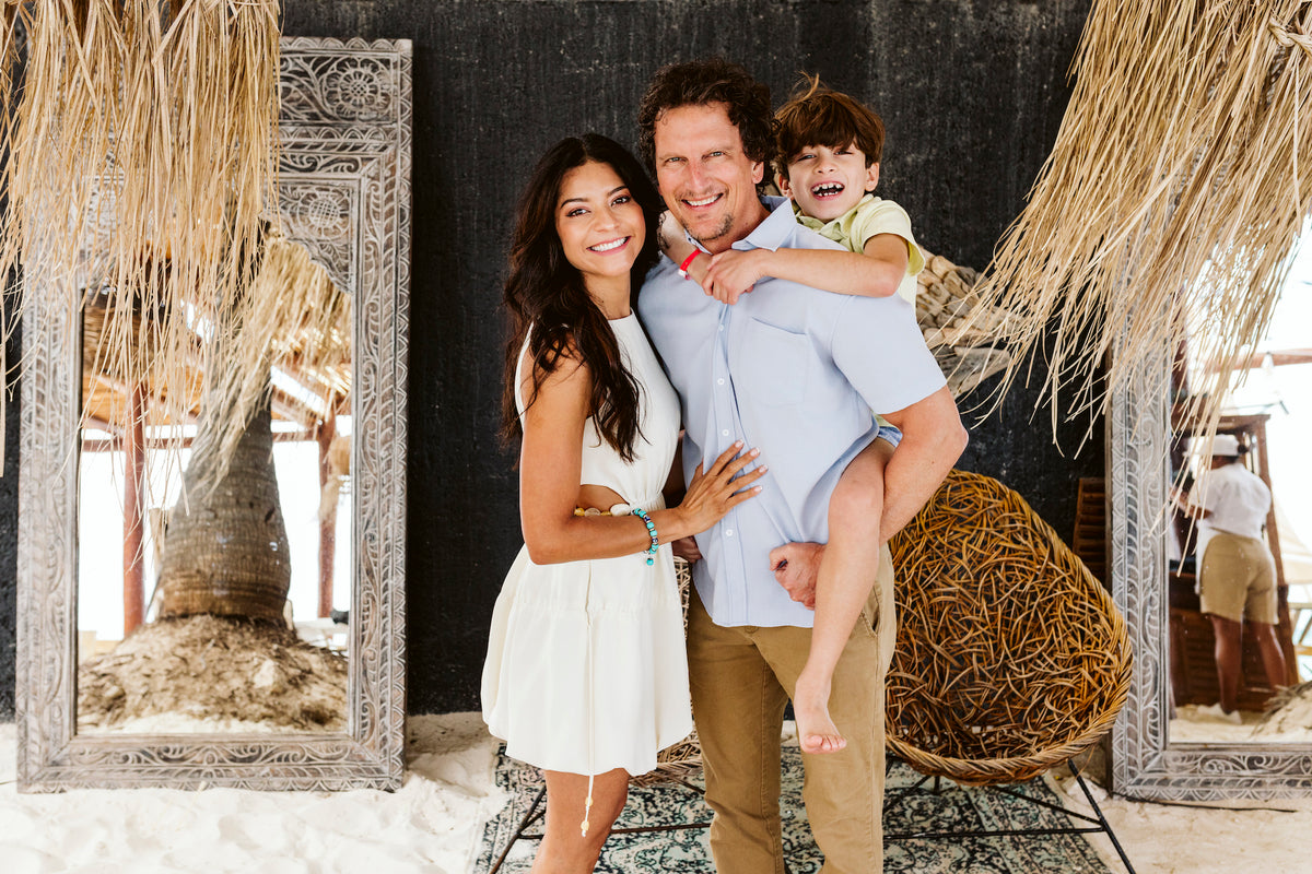 A family smiles together at Grand Fiesta Americana Coral Beach Cancún, the father carrying a boy piggyback