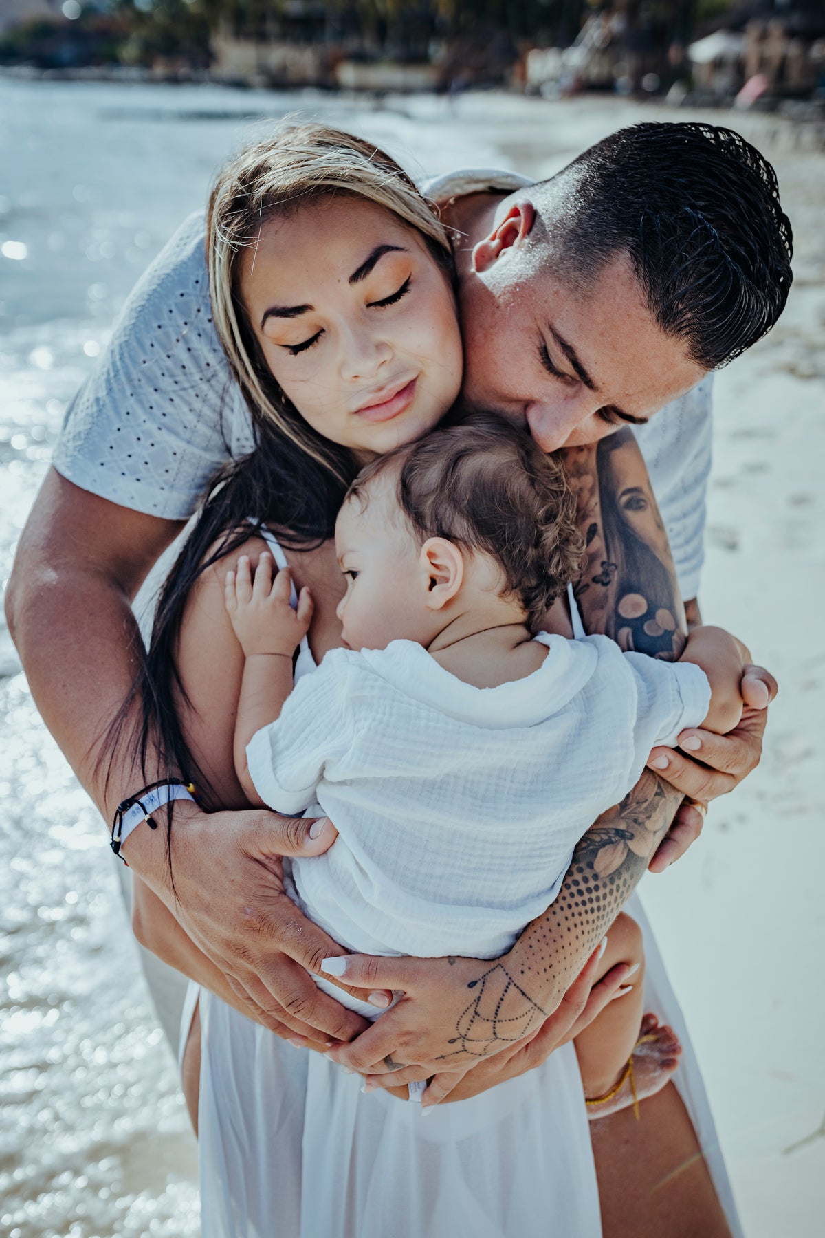 A couple embraces a baby on a beach at Grand Fiesta Americana Coral Beach Cancún