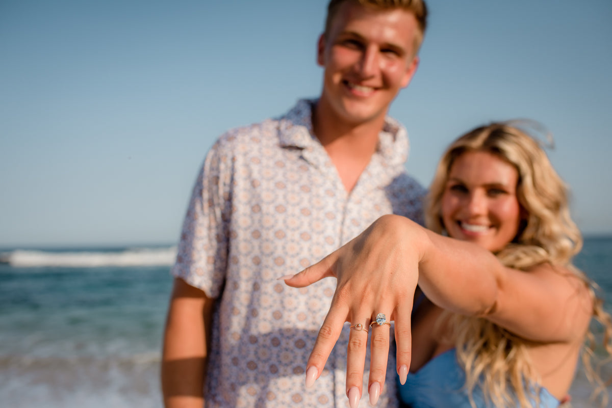 A woman shows her engagement ring while a couple smiles on the beach at Fiesta Americana Los Cabos