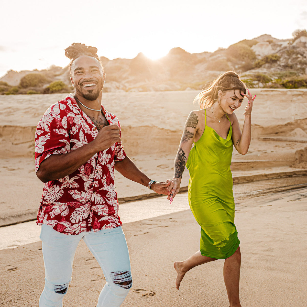 A couple holds hands walking on a sandy beach at Marquis Los Cabos during golden hour