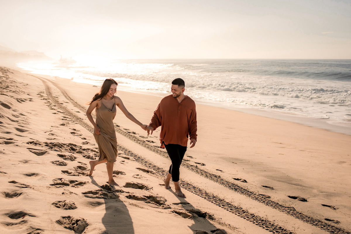 A couple holds hands walking barefoot on the beach at Marquis Los Cabos, Mexico