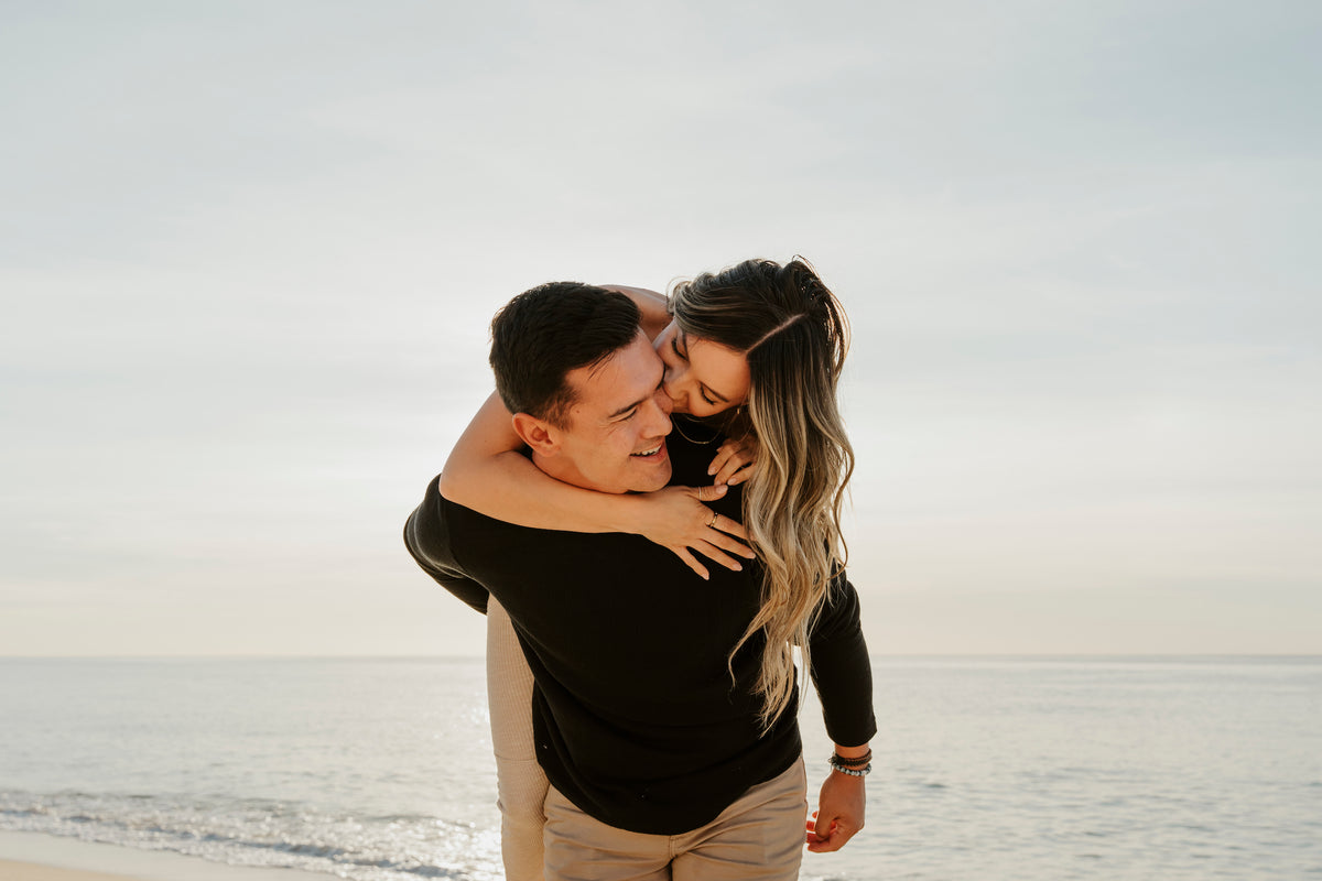 A woman gives a man a piggyback ride on the beach at Marquis Los Cabos, Mexico