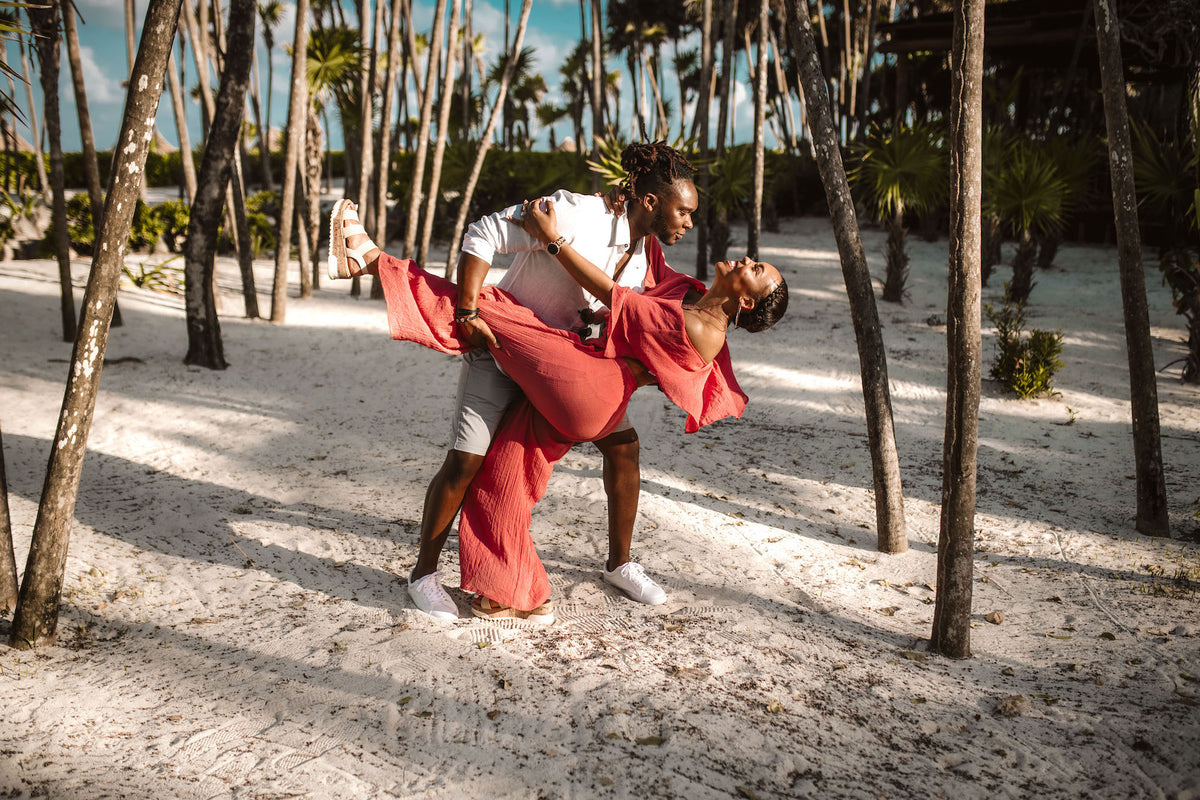 A man dips a woman in a red dress among palm trees at Valentin Imperial Riviera Maya