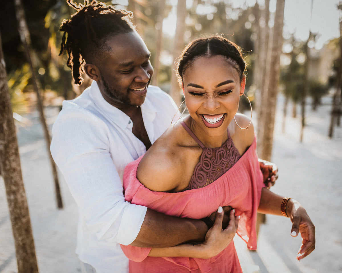 A couple laughing together outdoors among palm trees at Valentin Imperial Riviera Maya, Mexico
