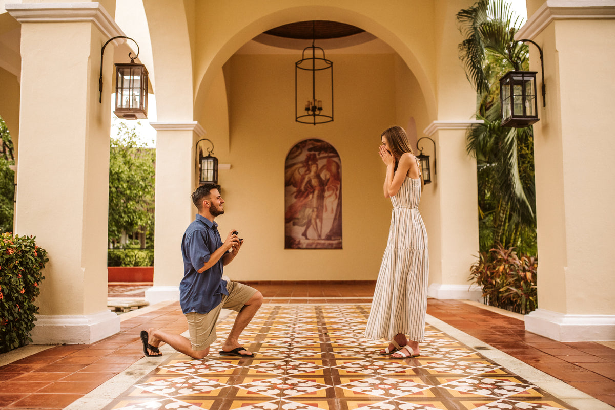 A man kneels proposing to a woman under an archway at Valentin Imperial Riviera Maya, Mexico