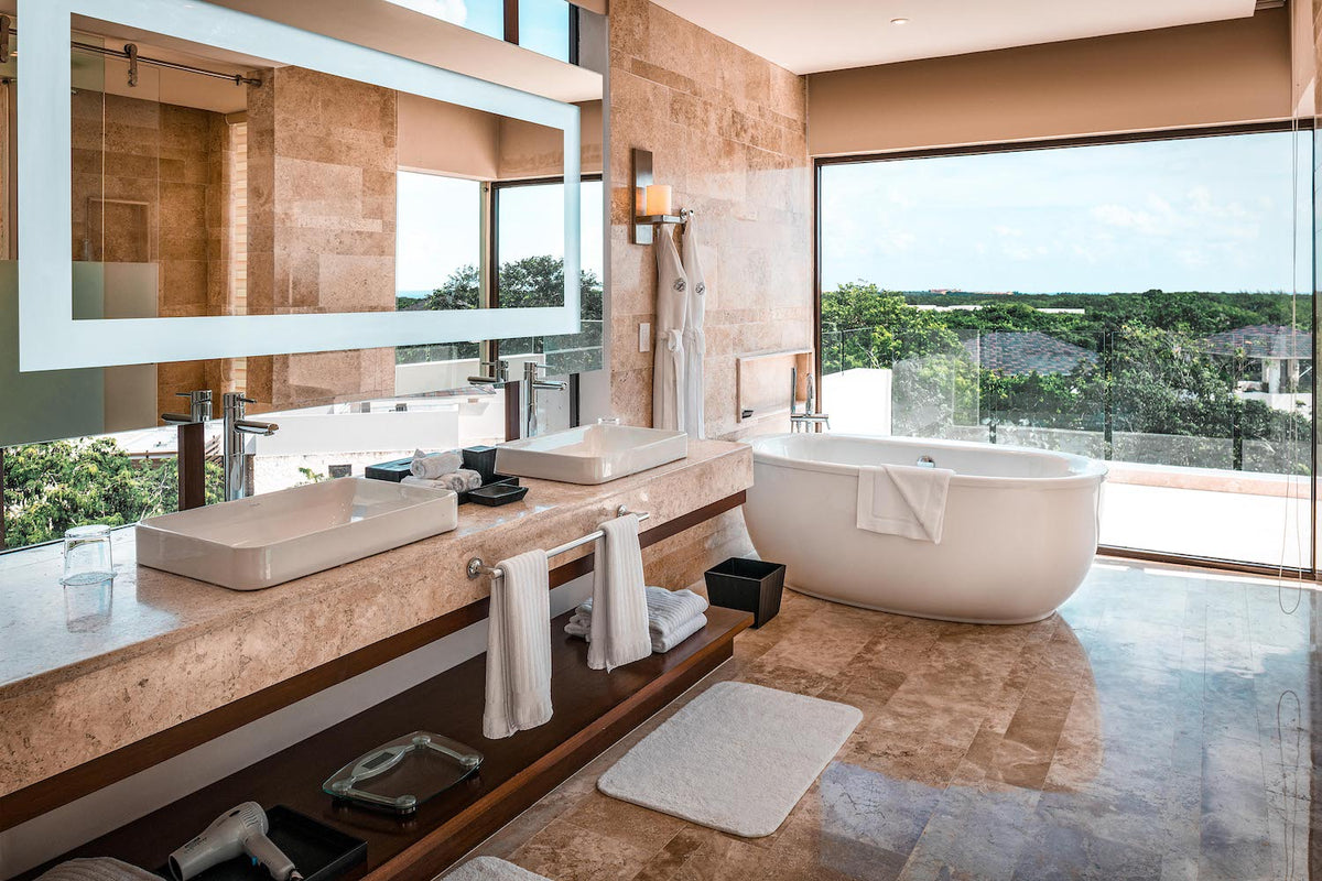 Luxury suite bathroom with a freestanding tub, double stone vanity and jungle-view windows