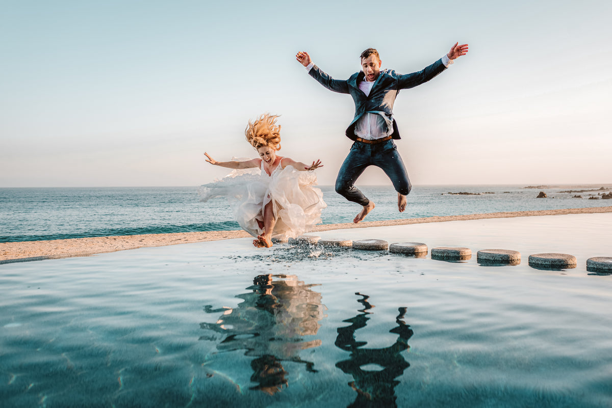 Couple with wedding suits jumping in the pool of Marquis Los Cabos