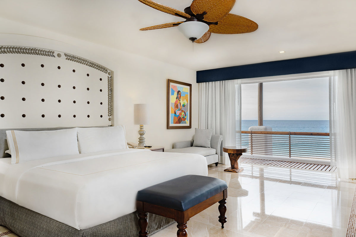 Ocean-view suite at Marquis Los Cabos with a king bed, colorful artwork and balcony over the sea