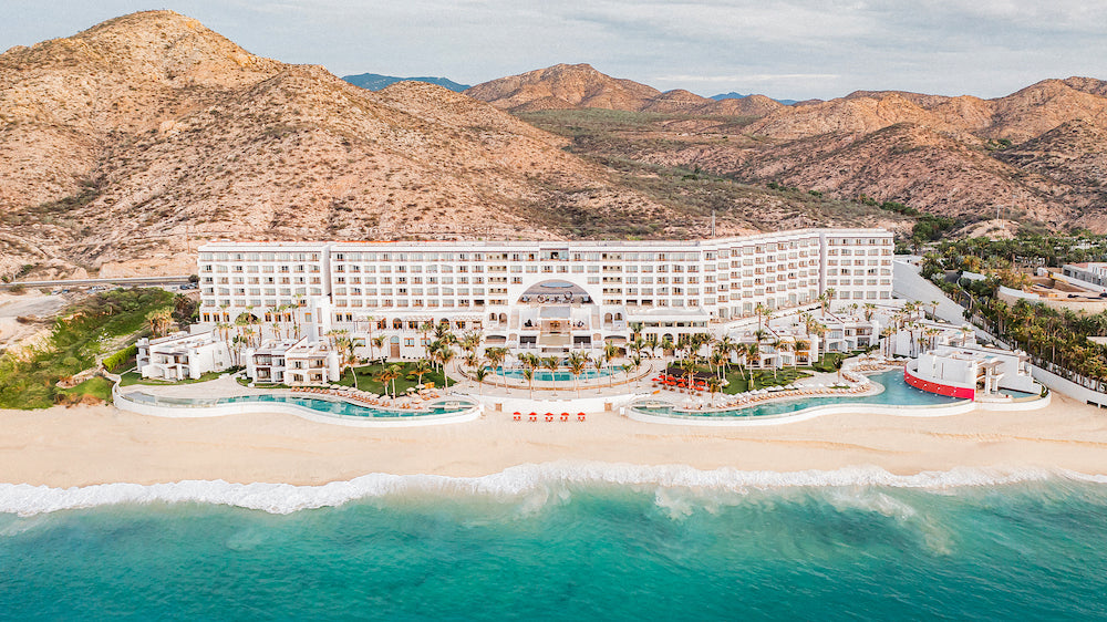 Aerial view of Marquis Los Cabos resort with pools, beach and desert mountains behind