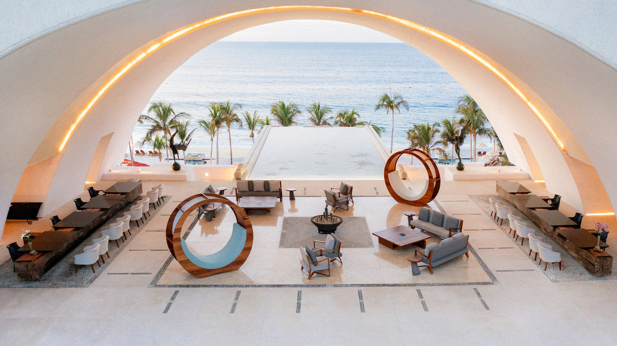 Hotel photography of the arched open-air lobby framing palm trees and the ocean at Marquis Los Cabos