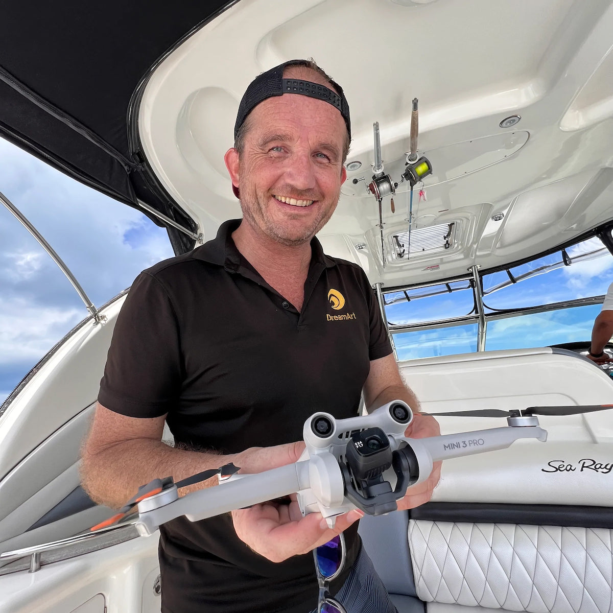 Smiling DreamArt drone pilot on a boat holds a DJI Mini 3 Pro drone