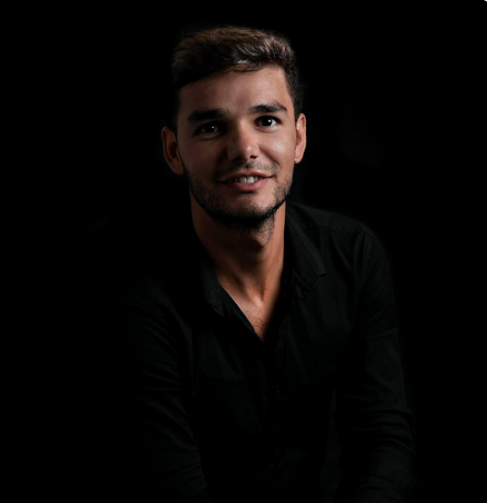 Smiling bootcamp instructor in a black shirt photographed against a dark background