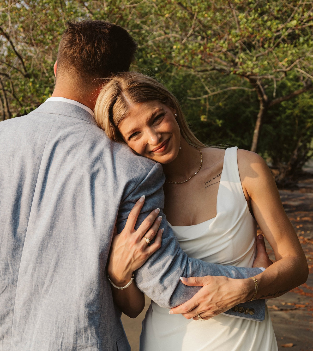 Smiling bride rests her head on the groom's shoulder beneath the trees at Secrets Papagayo Costa Rica