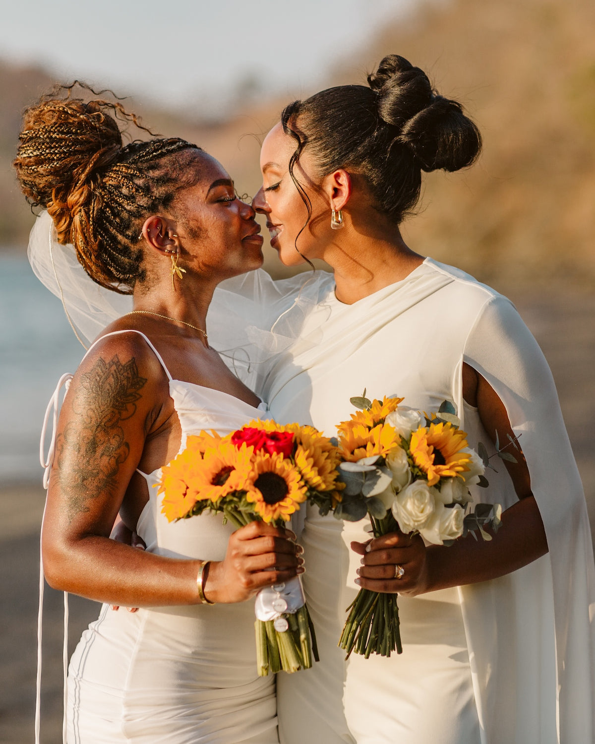Two brides with sunflower bouquets share a tender kiss on the beach at Secrets Papagayo Costa Rica