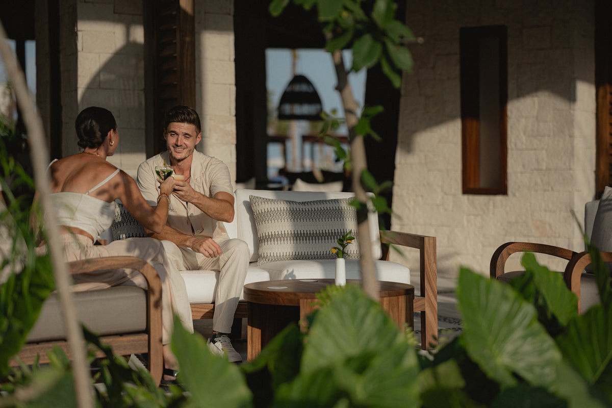 Couple shares a drink and a laugh on a shaded lounge terrace at Secrets Playa Blanca Costa Mujeres