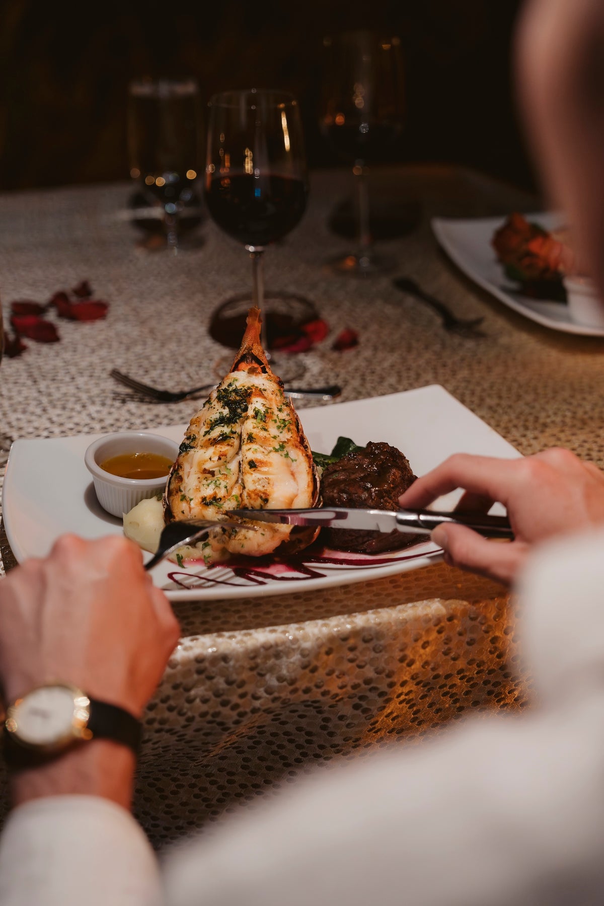 Guest slices a grilled lobster tail at a romantic red wine dinner at Secrets Papagayo Costa Rica