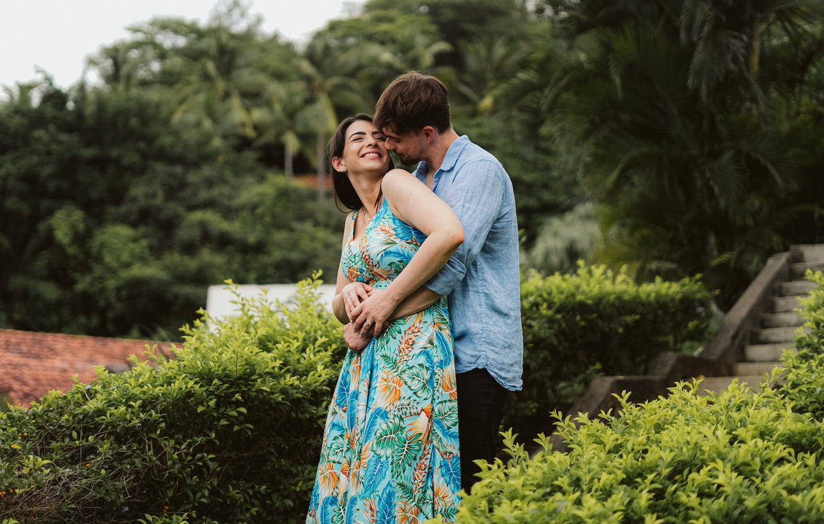 Couple hugs among green hedges and tropical trees during a lifestyle photoshoot at Secrets Papagayo
