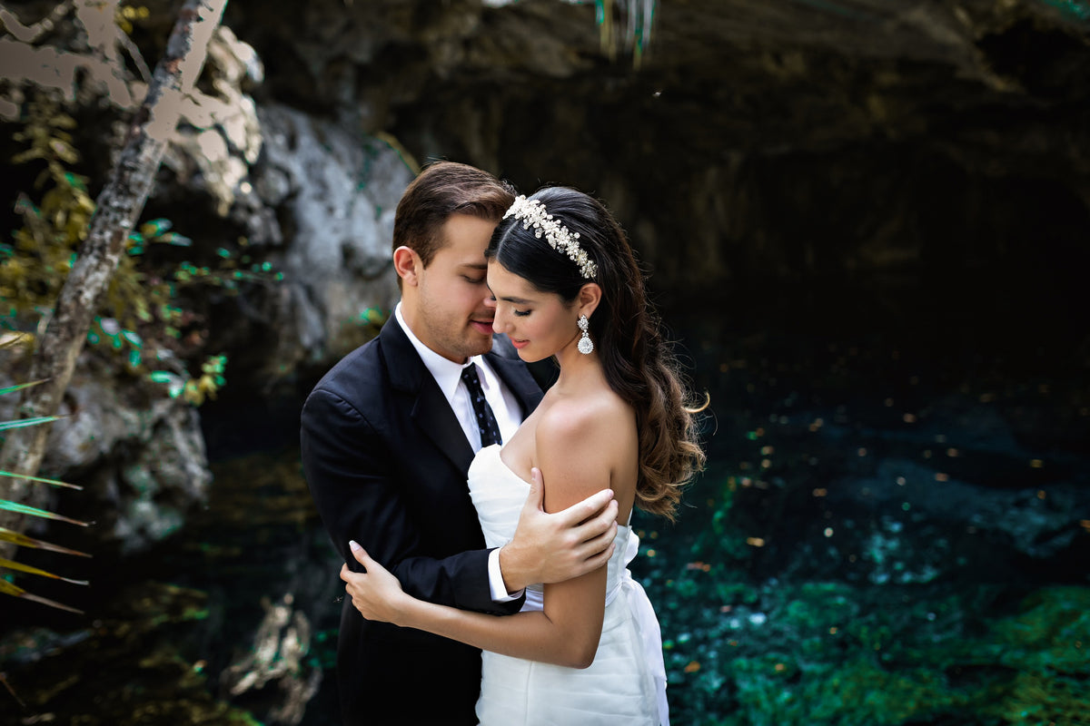 Bride and groom embrace beside the turquoise water of a cenote during a trash the dress photoshoot